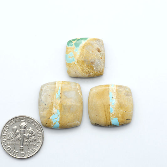 Three square royston stones with turquoise inclusions next to a U.S. dime dollar coin on a white background