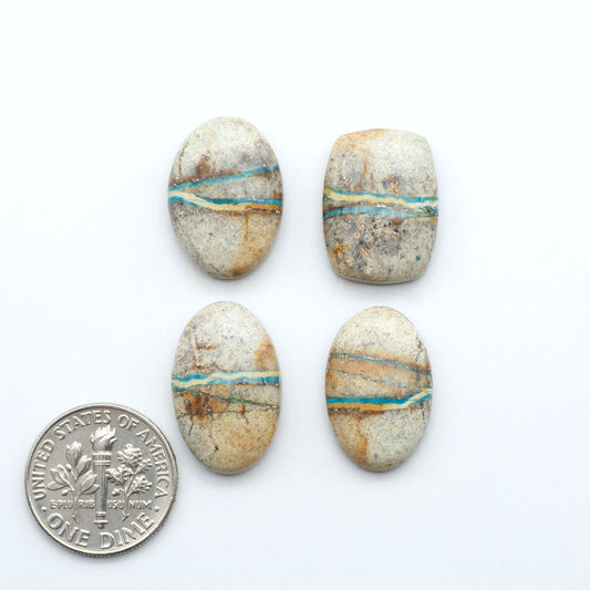 Four oval royston turquoise stones with blue and gold vein patterns next to a U.S. dime on a white background