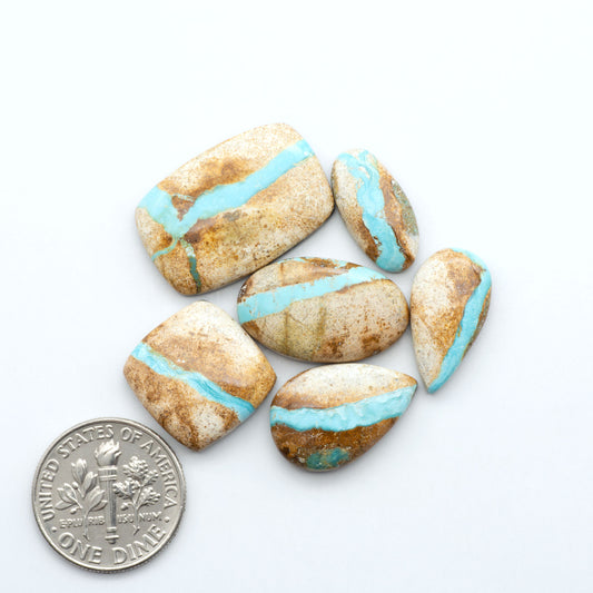 blue green royston ribbon turquoise stones on a white background next to us dime for size comparison