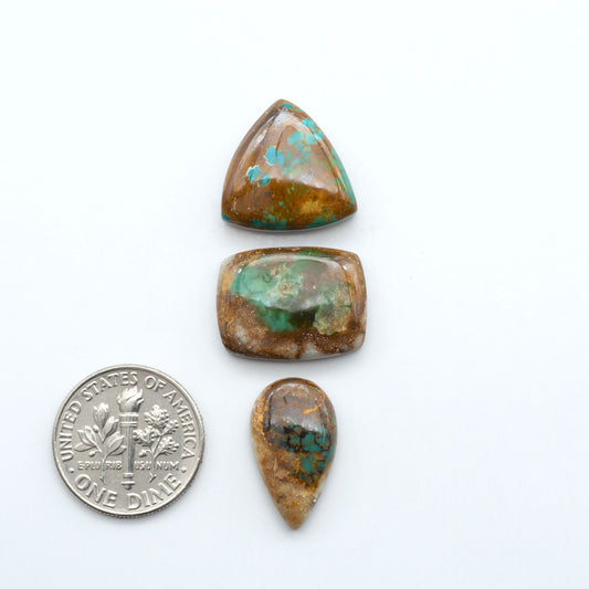 3 green royston turquoise stones on a white background next to us dime for size comparison