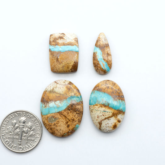 four blue green royston ribbon turquoise stones on a white background next to us dime for size comparison