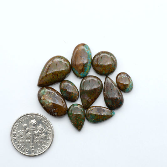 Sonoran Mountain turquoise cabochon lot green stones on white background with U.S. dime for size.