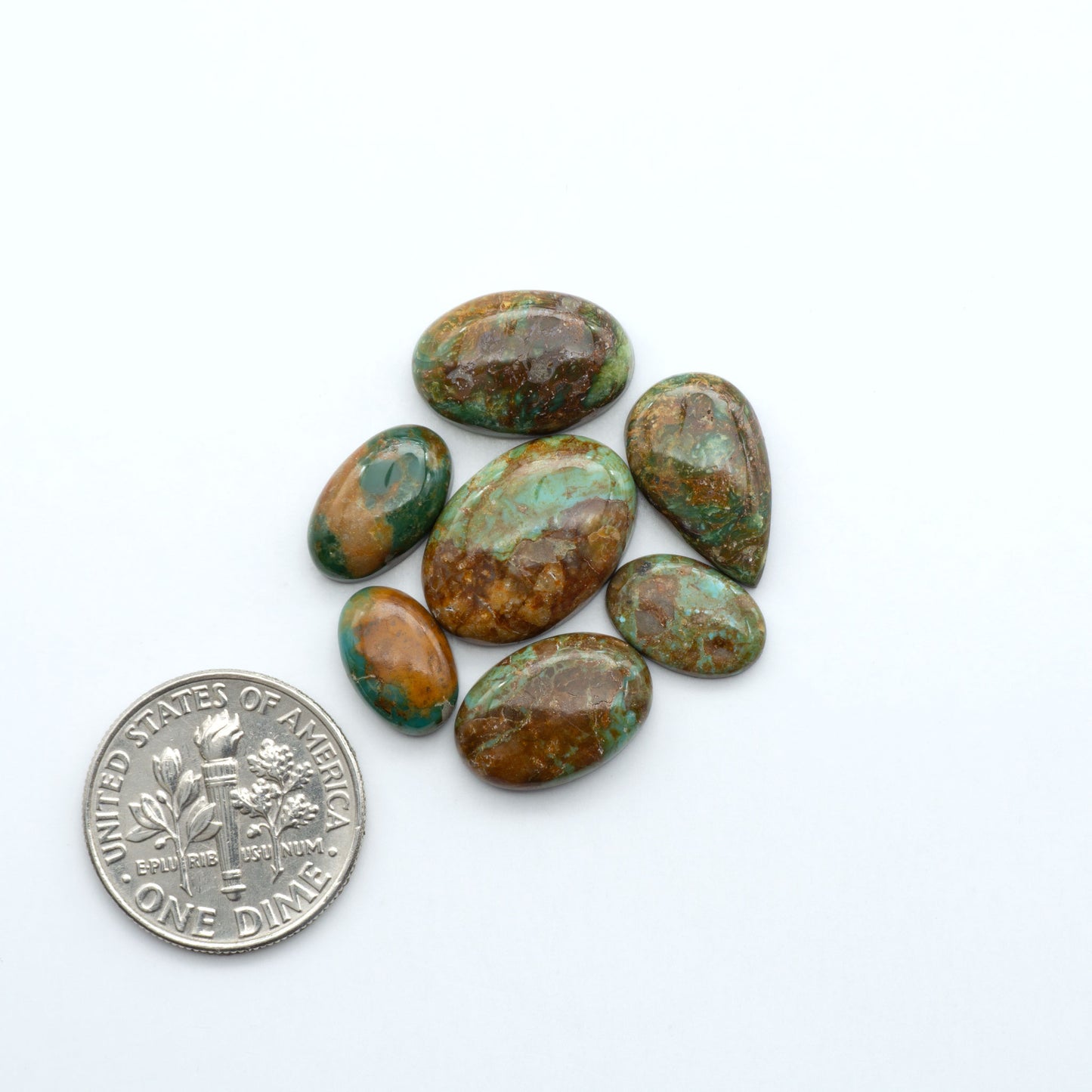 Sonoran Mountain turquoise cabochon lot blue green stones on white background with U.S. dime for size.