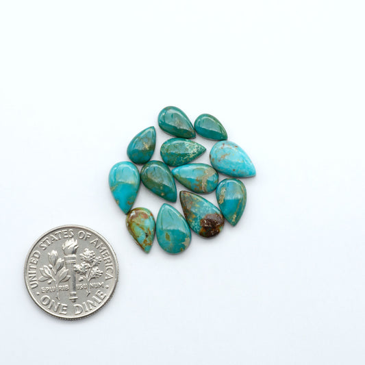 Sonoran Mountain turquoise cabochon lot blue green stones on white background with U.S. dime for size.