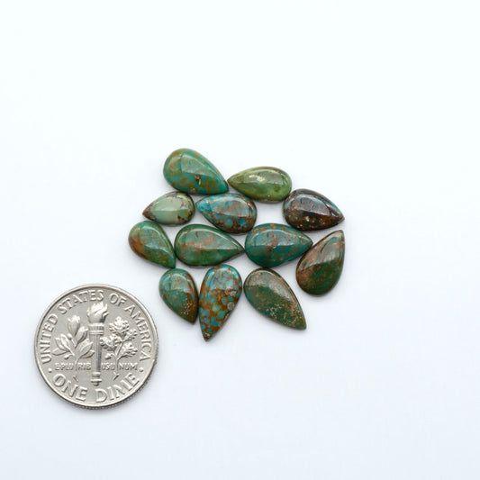 Sonoran Mountain turquoise cabochon lot green stones on white background with U.S. dime for size.