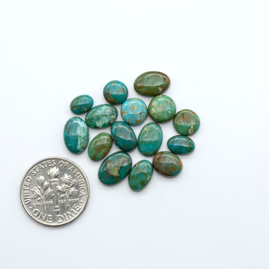 Sonoran Mountain turquoise cabochon lot blue green stones on white background with U.S. dime for size.