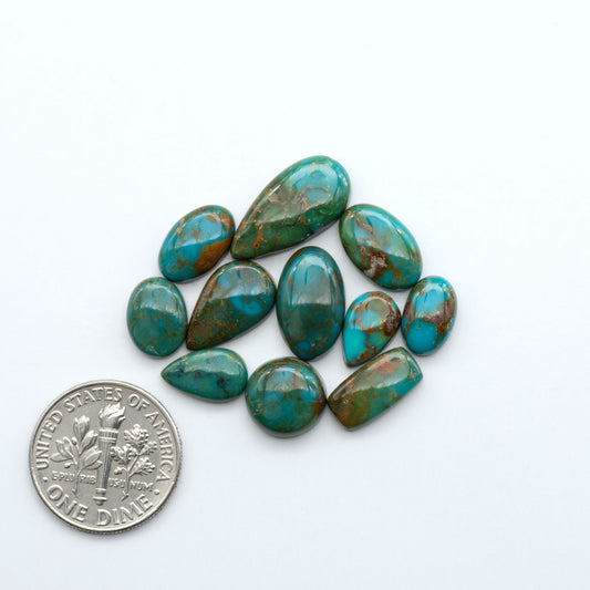 Sonoran Mountain turquoise cabochon lot blue green stones on white background with U.S. dime for size.