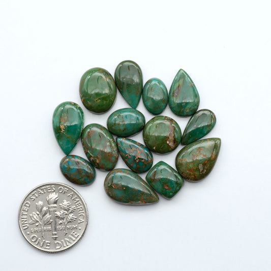 Sonoran Mountain turquoise cabochon lot green stones on white background with U.S. dime for size.