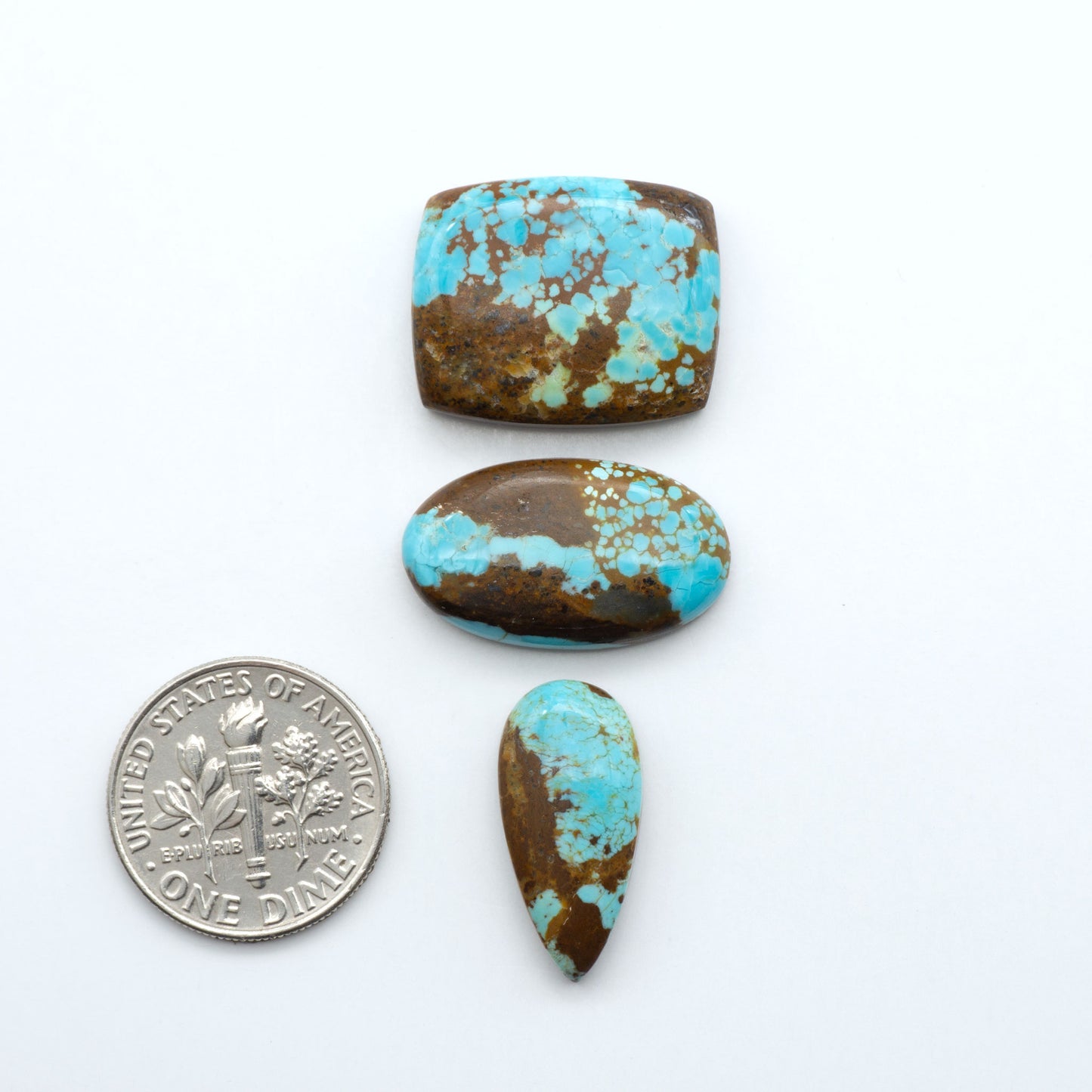 Number 8 turquoise cabochons with brown matrix on a white background shown with U.S. dime for size.