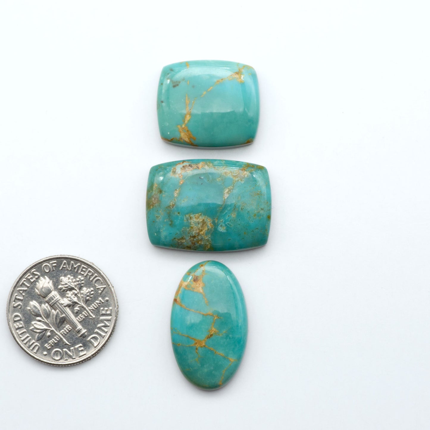 Turquoise Mountain turquoise cabochons, blue and green colors with natural matrix, polished stones on a white background, with a US dime for scale