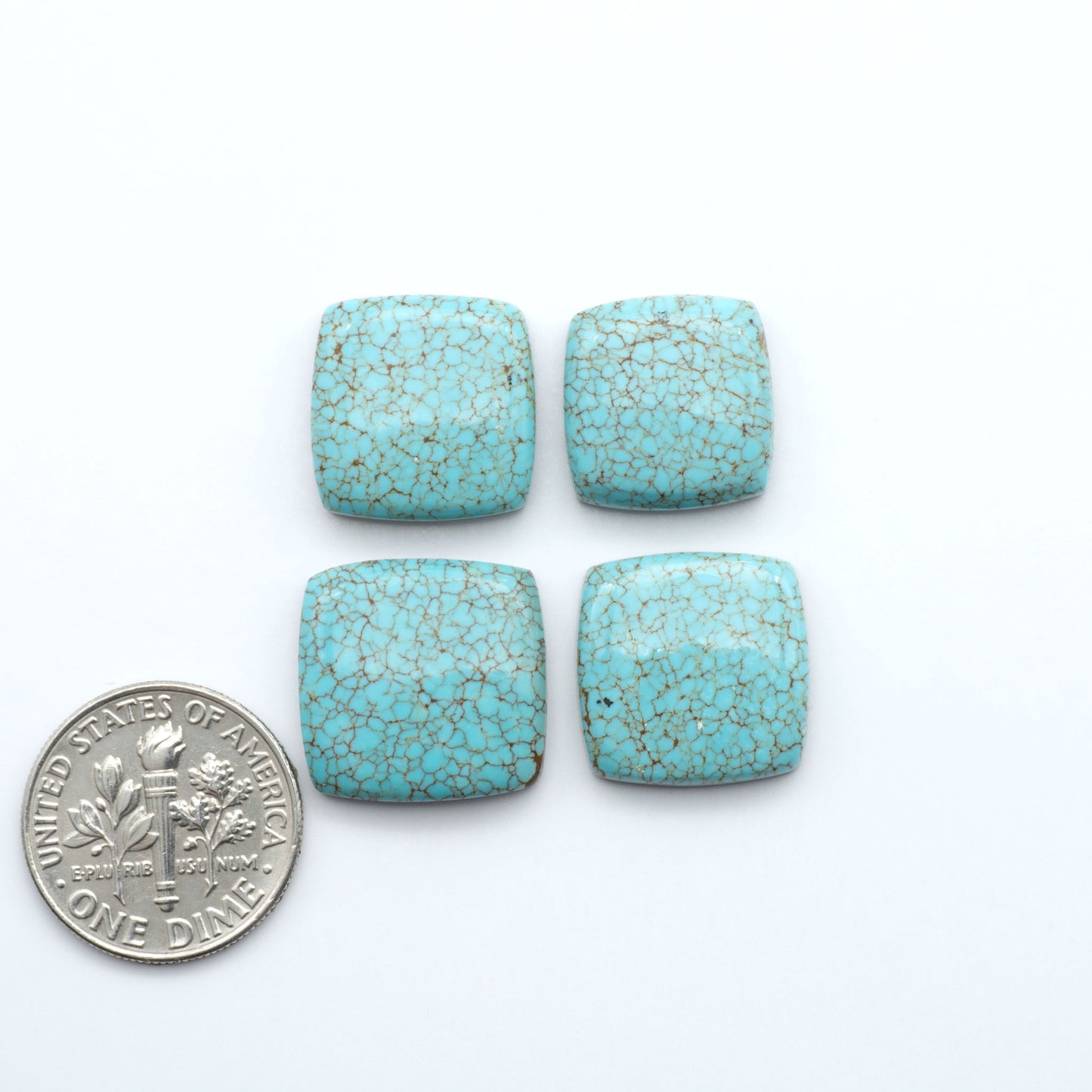 Number 8 turquoise cabochons, classic color with distinctive matrix, polished stones on white background with US dime for scale