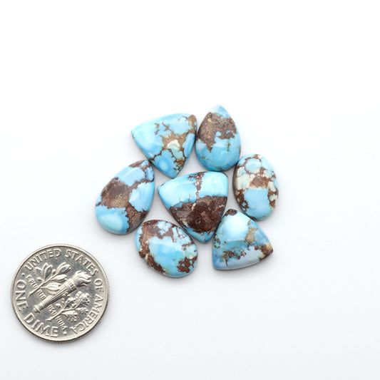 Golden Hills Turquoise cabochons, icy blue to lavender tones with chocolate matrix, polished stones on a white background with a US dime for scale