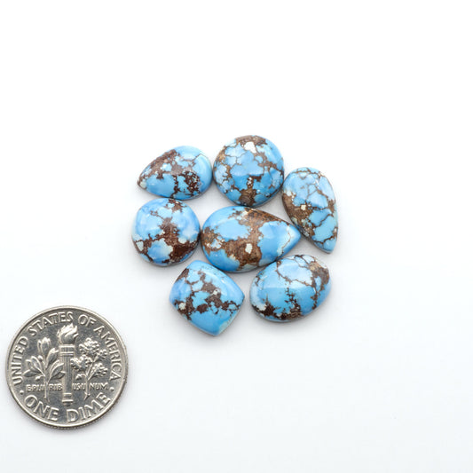 Golden Hills Turquoise cabochons, icy blue to lavender tones with chocolate matrix, polished stones on a white background with a US dime for scale