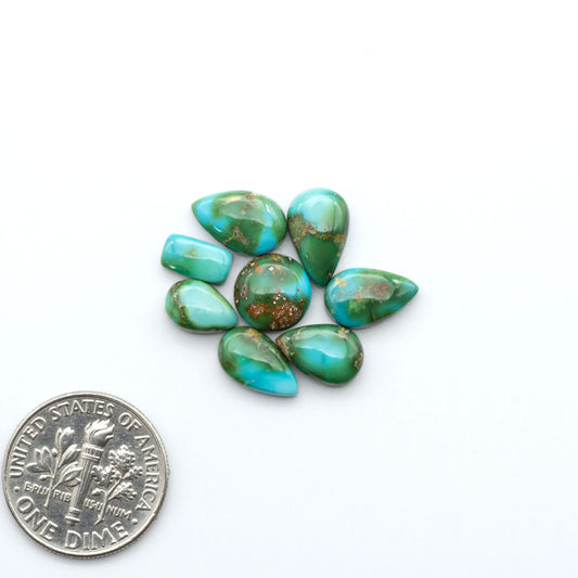 Sonoran Mountain Turquoise cabochons, blue-green color with natural matrix, polished stones on a white background with a US dime for scale