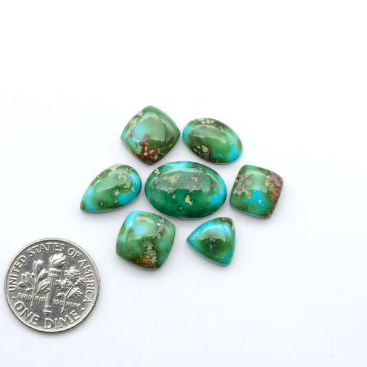 Sonoran Mountain Turquoise cabochons, blue-green color with natural matrix, polished stones on a white background with a US dime for scale