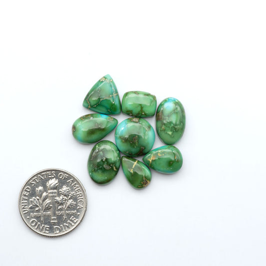 Sonoran Mountain Turquoise cabochons, blue-green color with natural matrix, polished stones on a white background with a US dime for scale