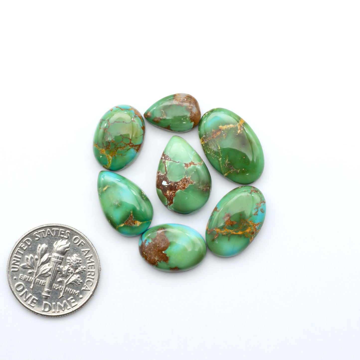 Sonoran Mountain Turquoise cabochons, blue-green color with natural matrix, polished stones on a white background with a US dime for scale