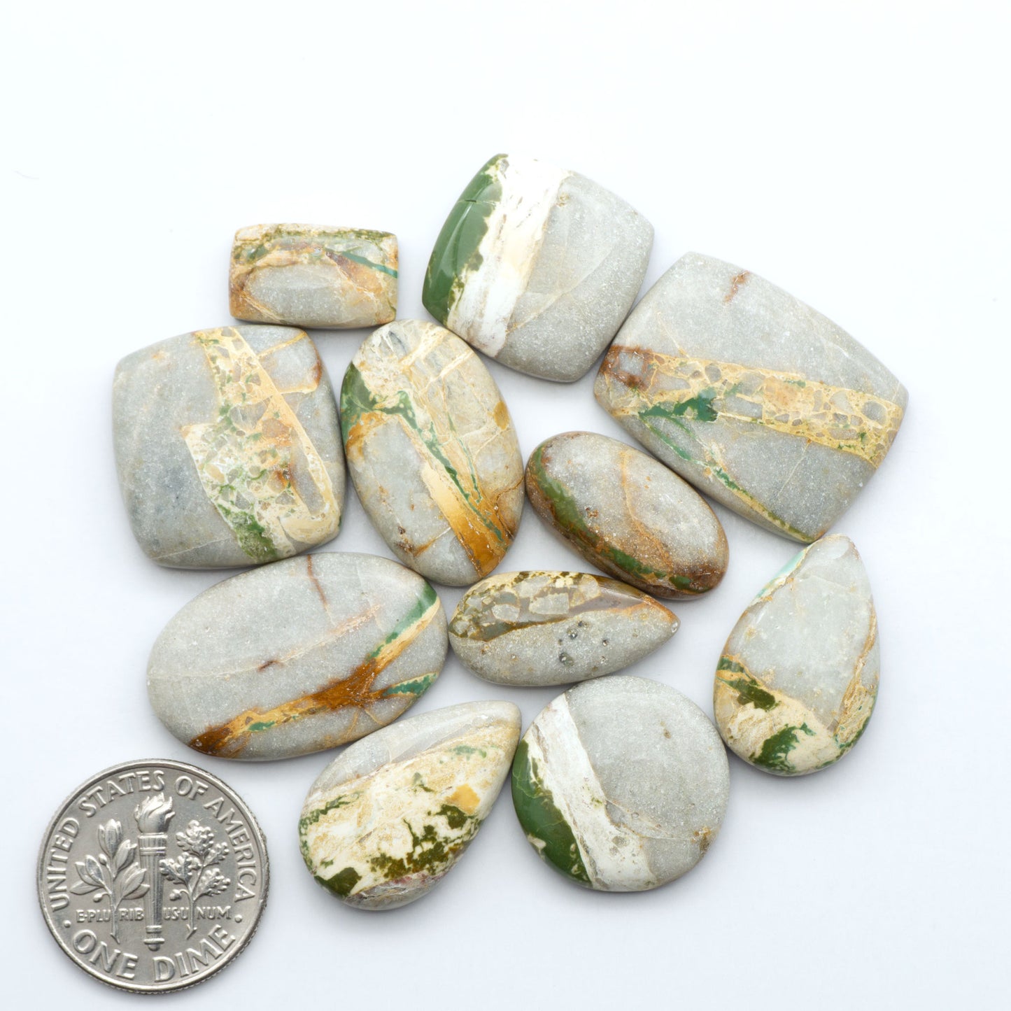 Royston Turquoise cabochons, blue-green color with natural matrix, polished stones on a white background, with a US dime for scale