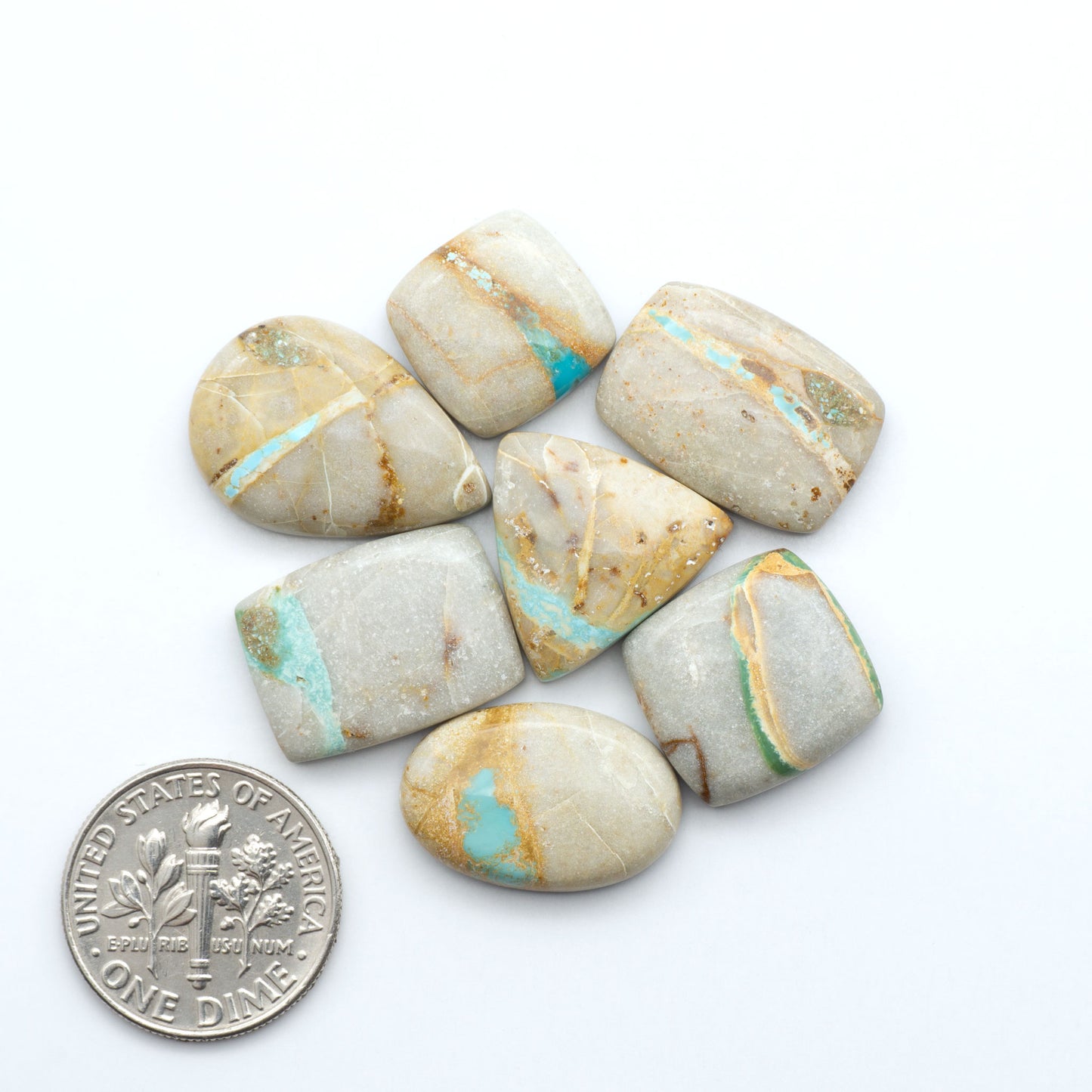 Royston Turquoise cabochons, blue-green color with natural matrix, polished stones on a white background, with a US dime for scale