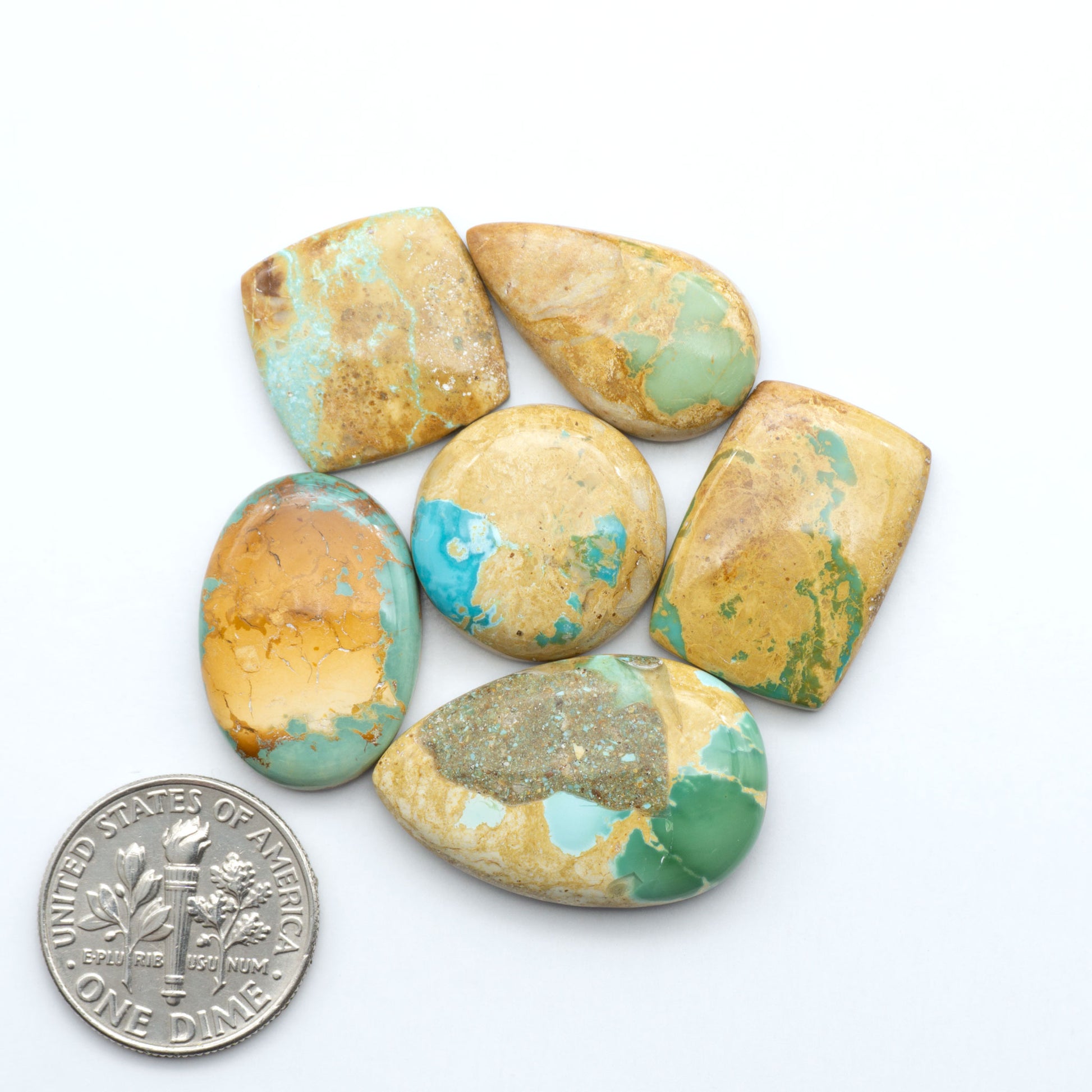 Royston Turquoise cabochons, blue-green color with natural matrix, polished stones on a white background, with a US dime for scale