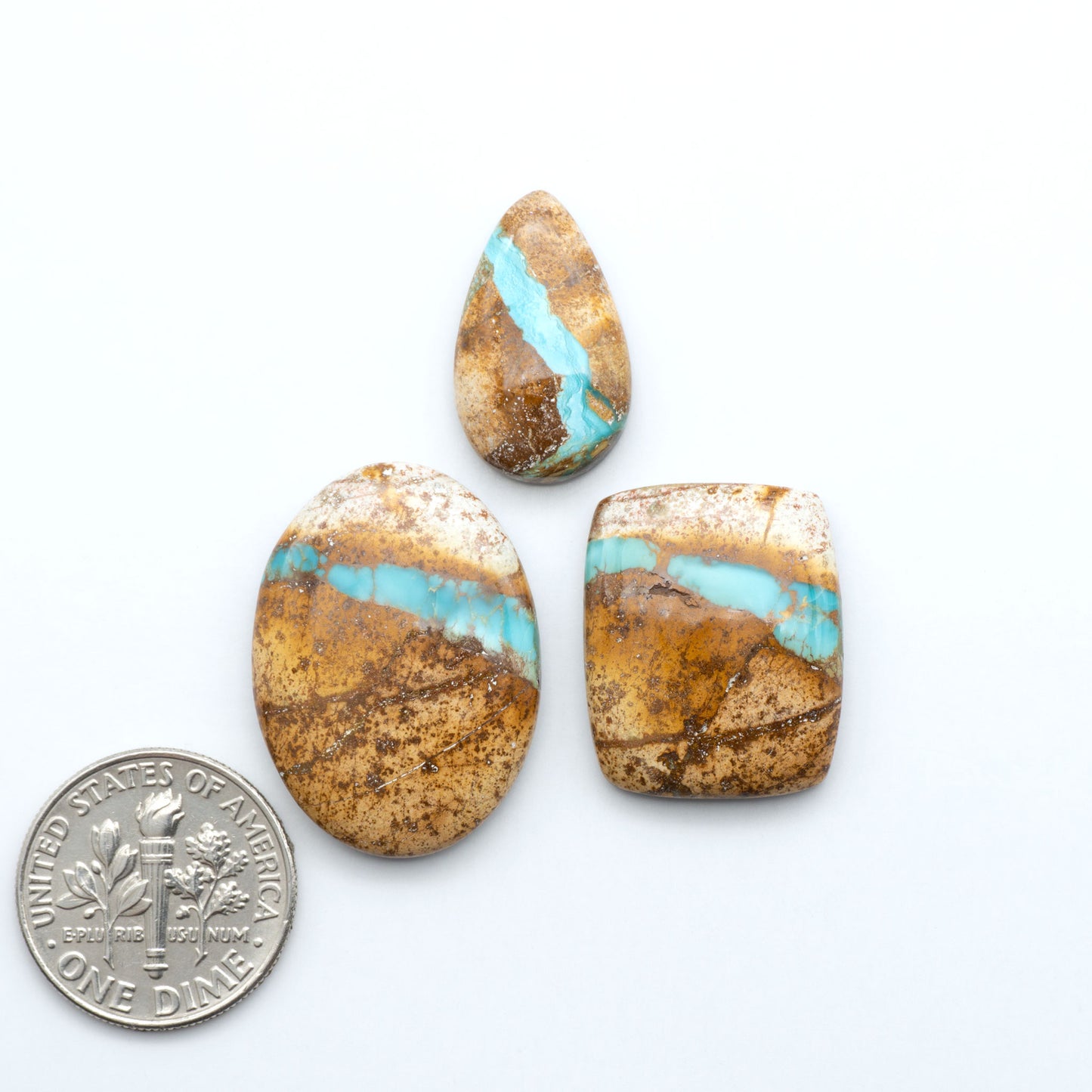 Royston Turquoise cabochons, blue-green color with natural matrix, polished stones on a white background, with a US dime for scale