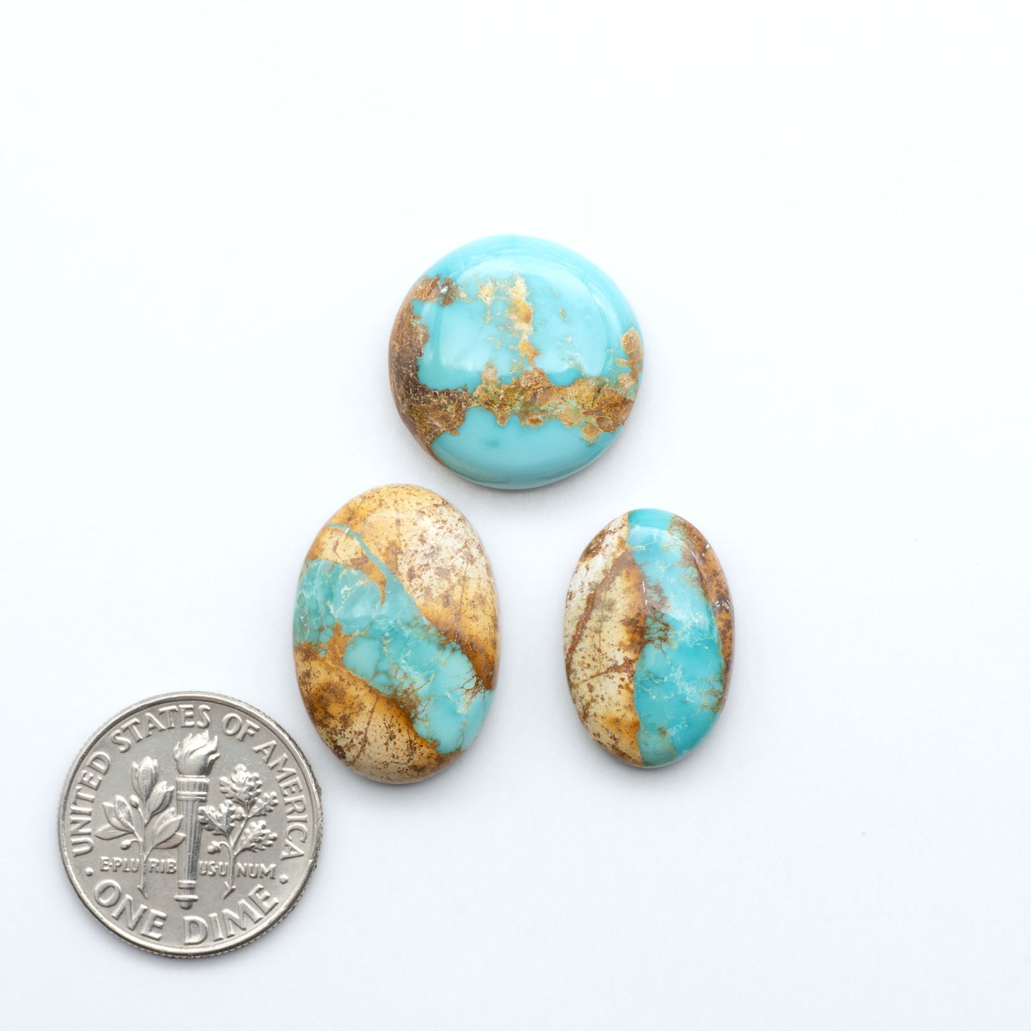 Royston Turquoise cabochons, blue-green color with natural matrix, polished stones on a white background, with a US dime for scale
