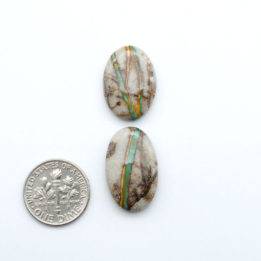 Royston Turquoise cabochons, blue-green color with natural matrix, polished stones on a white background, with a US dime for scale