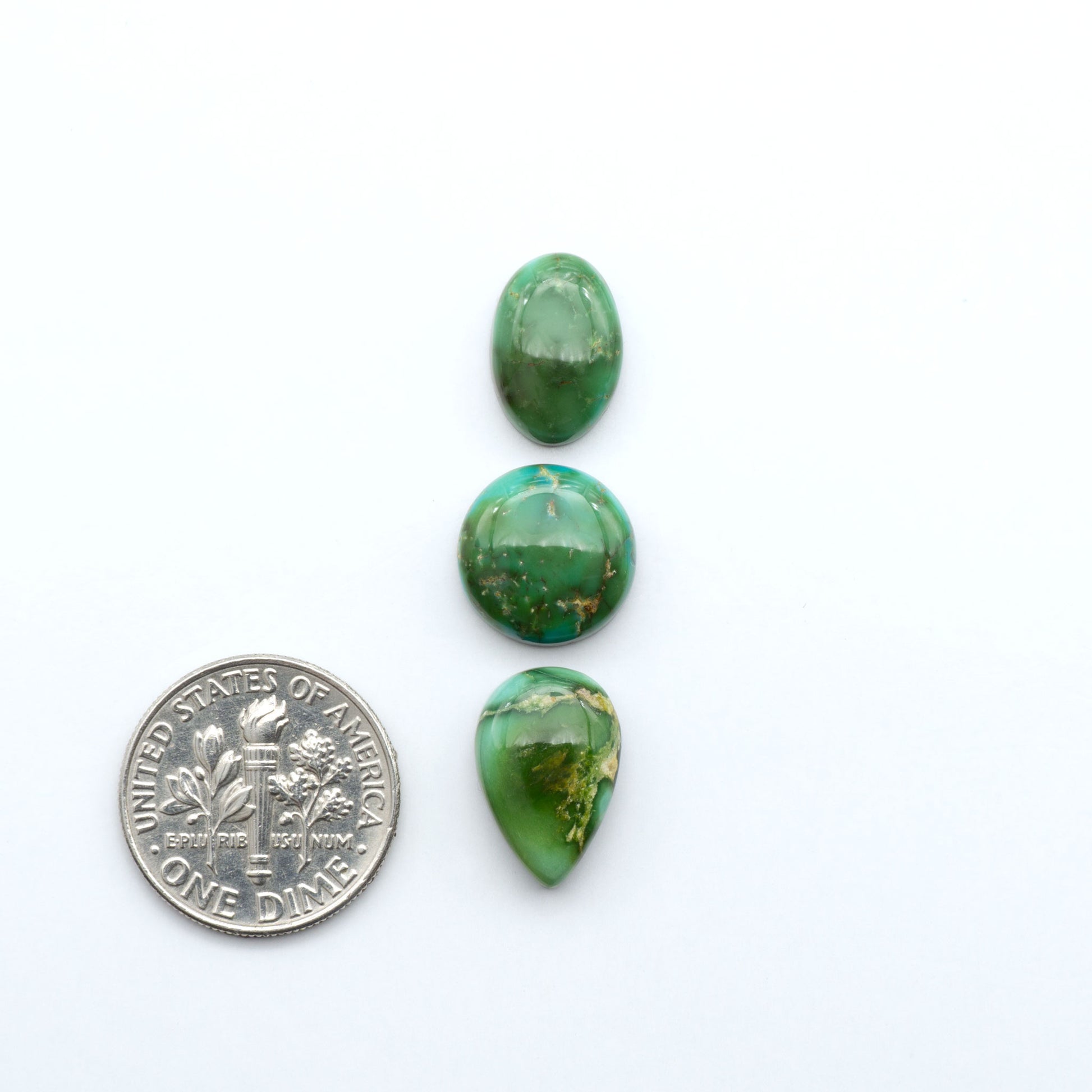 Sonoran Mountain Turquoise cabochons, blue and green color with natural matrix, polished stones on a white background, with a US dime for scale