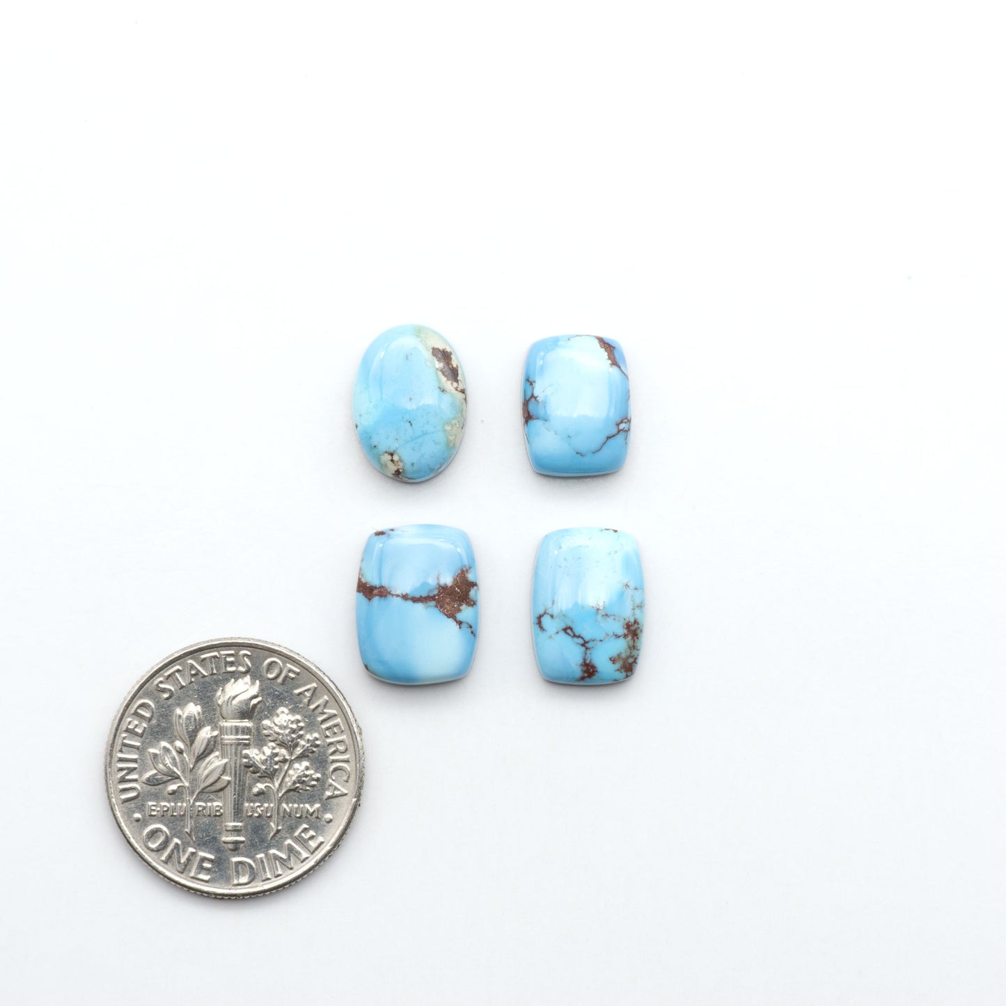 Golden Hills Turquoise cabochons, icy blue to lavender tones with chocolate matrix, polished stones on a white background with a US dime for scale