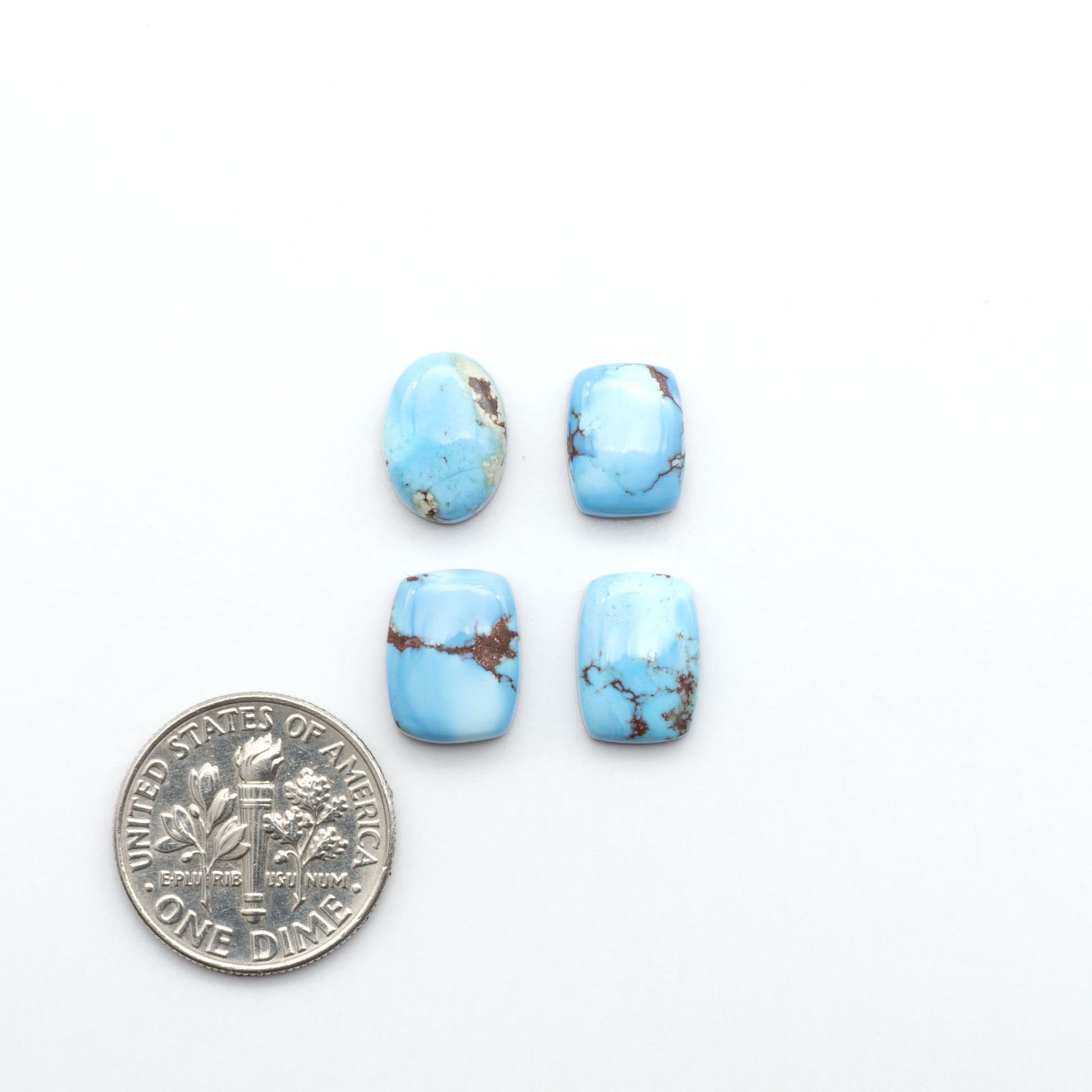 Golden Hills Turquoise cabochons, icy blue to lavender tones with chocolate matrix, polished stones on a white background with a US dime for scale