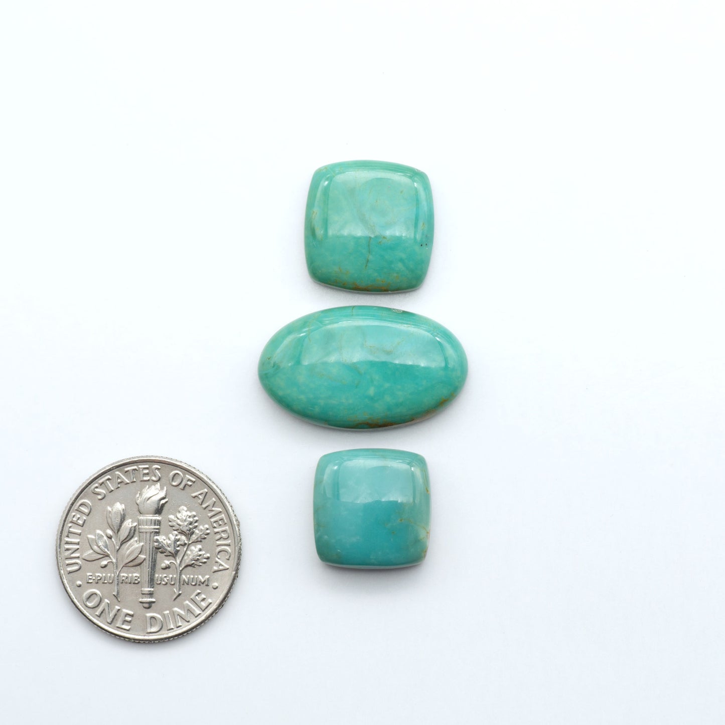 Turquoise Mountain Turquoise cabochons, blue and green colors with natural matrix, polished stones on a white background, with a US dime for scale