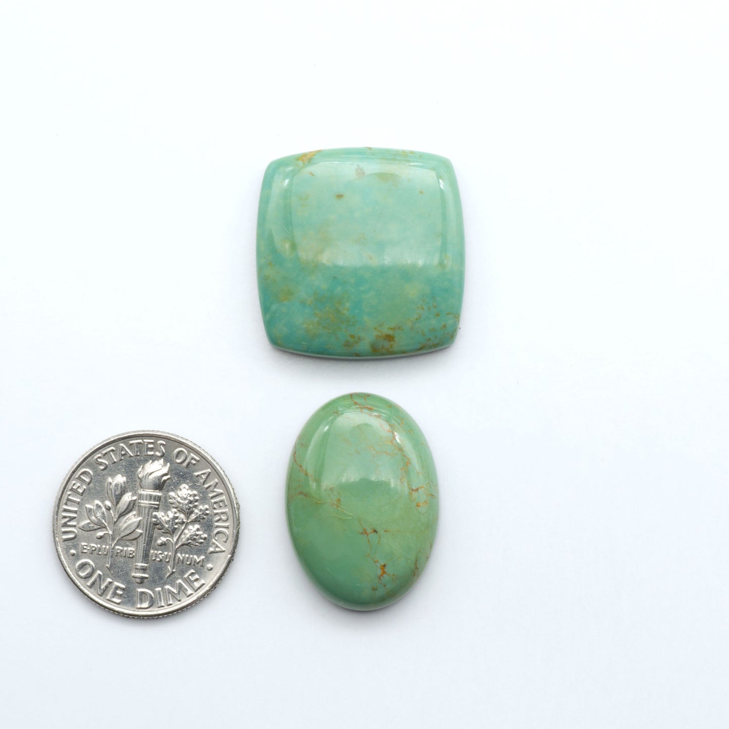 Turquoise Mountain Turquoise cabochons, blue and green colors with natural matrix, polished stones on a white background, with a US dime for scale