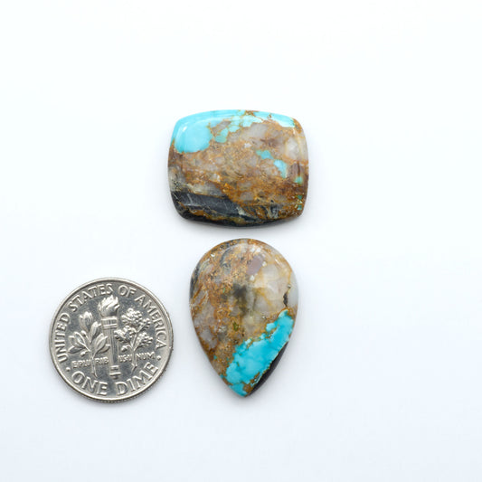Black Jack turquoise cabochons, blue-green color with black matrix, polished stones on a white background with a US dime for scale