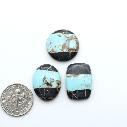 Black Jack turquoise cabochons, blue-green color with black matrix, polished stones on a white background with a US dime for scale