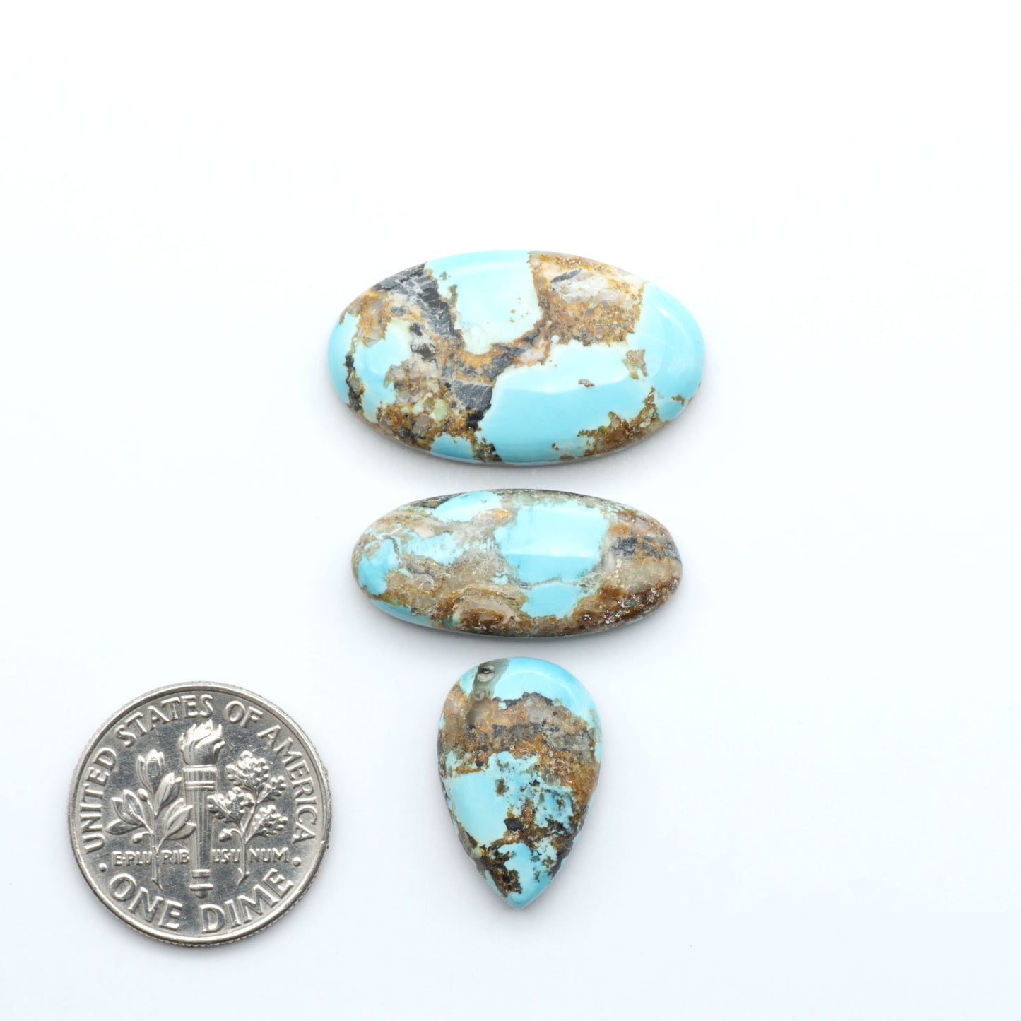 Black Jack turquoise cabochons, blue-green color with black matrix, polished stones on a white background with a US dime for scale