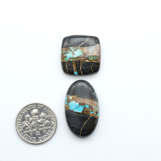 Black Jack turquoise cabochons, blue-green color with black matrix, polished stones on a white background with a US dime for scale