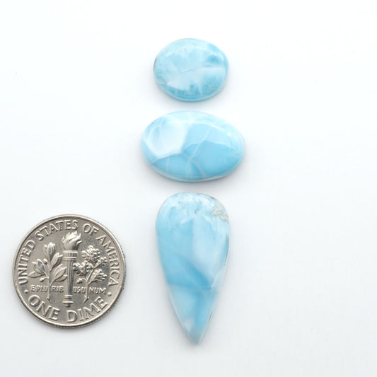 Larimar stone cabochons, cut and polished, blue and white gemstones on a white background, with a US dime for scale