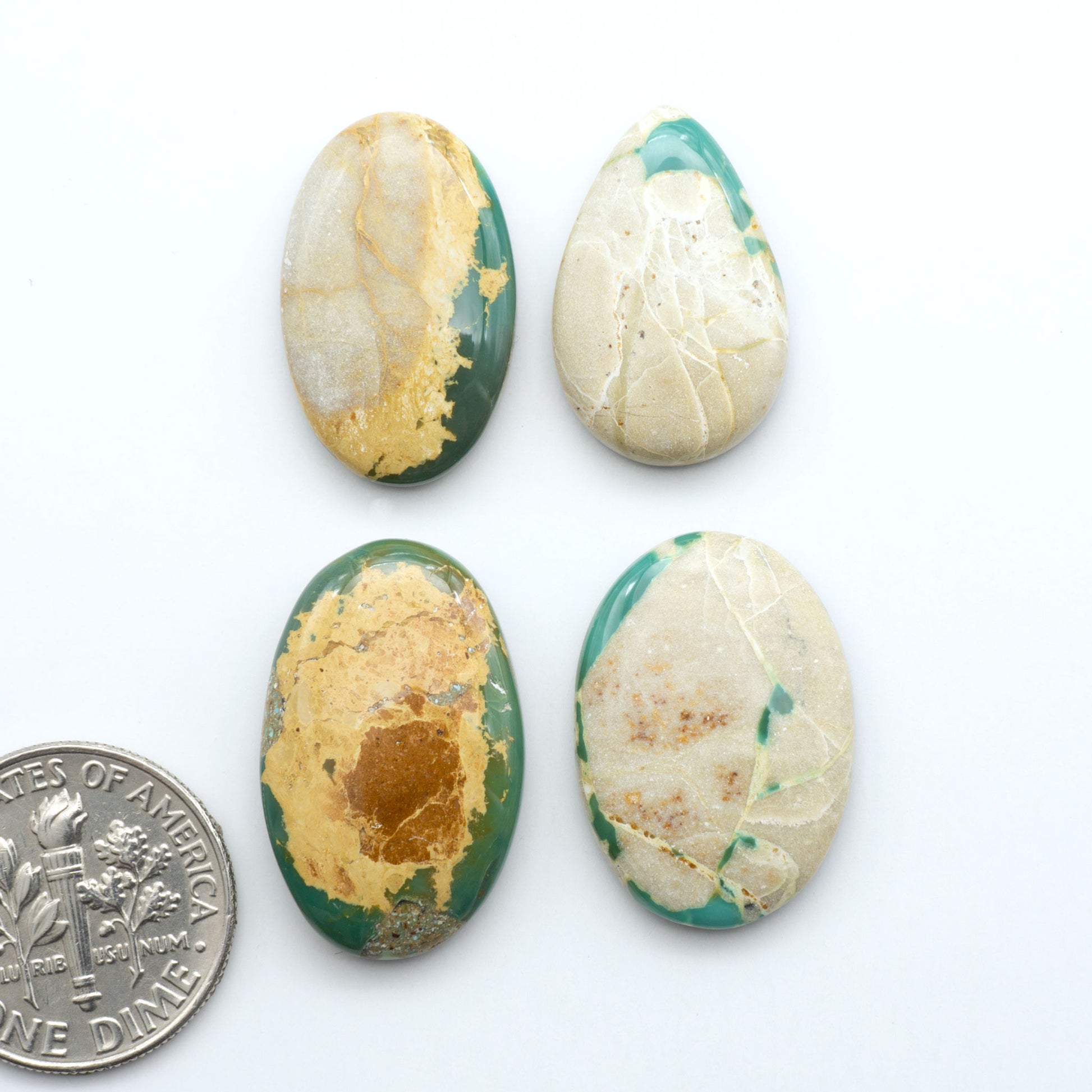 Royston Turquoise cabochons, blue-green color with natural matrix, polished stones on a white background, with a US dime for scale