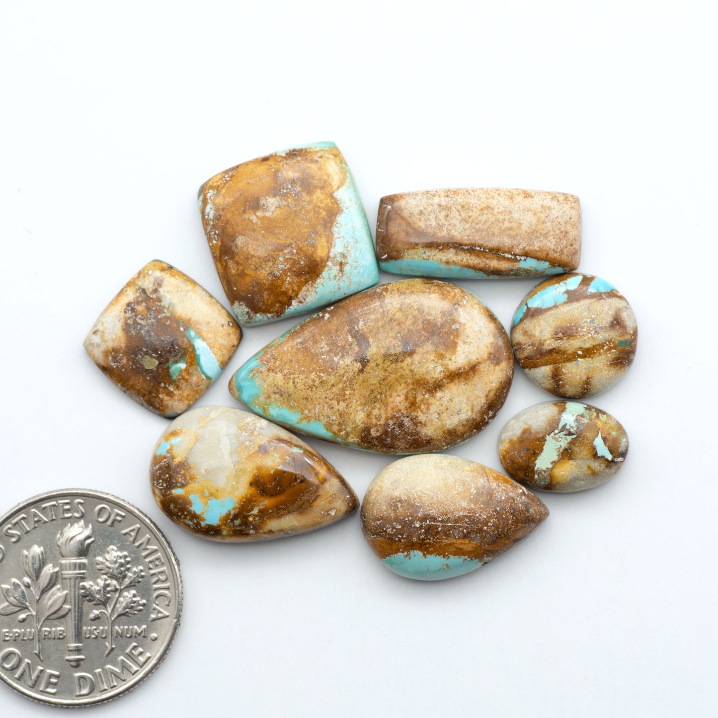 Royston Turquoise cabochons, blue-green color with natural matrix, polished stones on a white background, with a US dime for scale