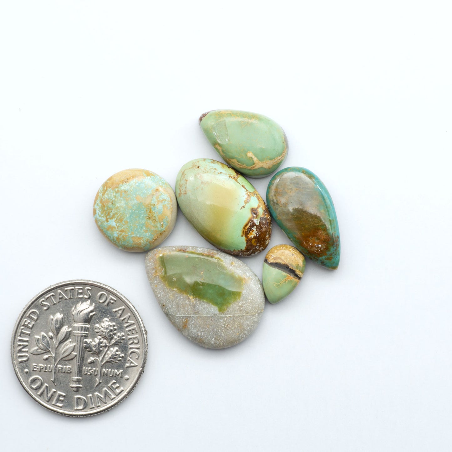 Royston Turquoise cabochons, blue-green color with natural matrix, polished stones on a white background, with a US dime for scale