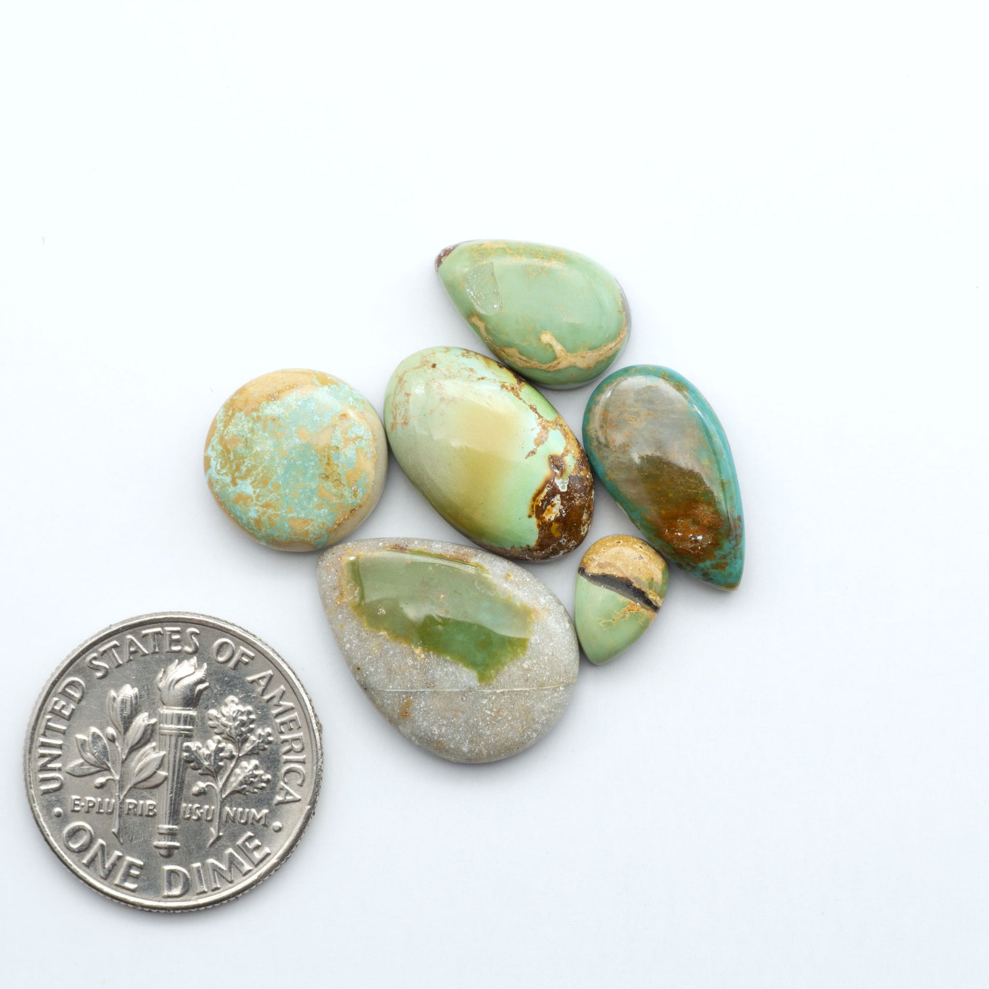 Royston Turquoise cabochons, blue-green color with natural matrix, polished stones on a white background, with a US dime for scale
