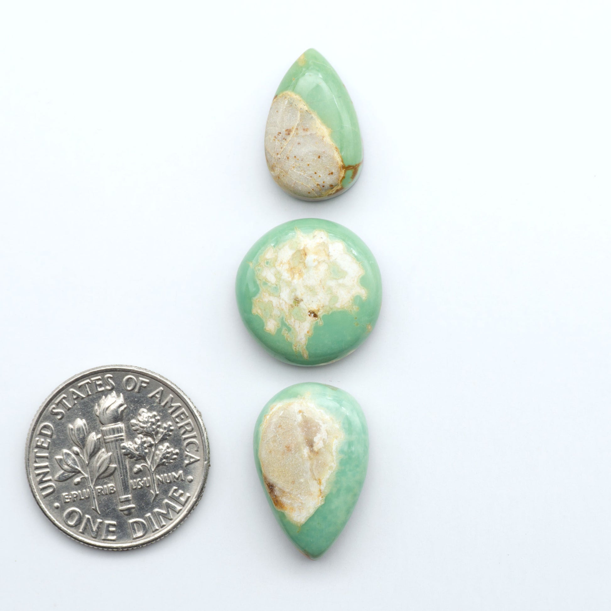 Royston Turquoise cabochons, blue-green color with natural matrix, polished stones on a white background, with a US dime for scale