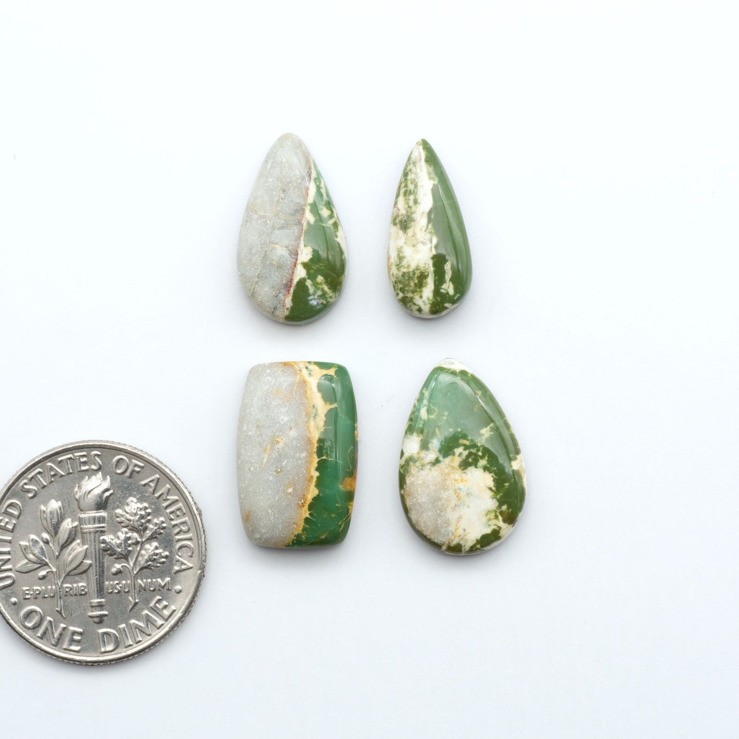 Royston Turquoise cabochons, blue-green color with natural matrix, polished stones on a white background, with a US dime for scale