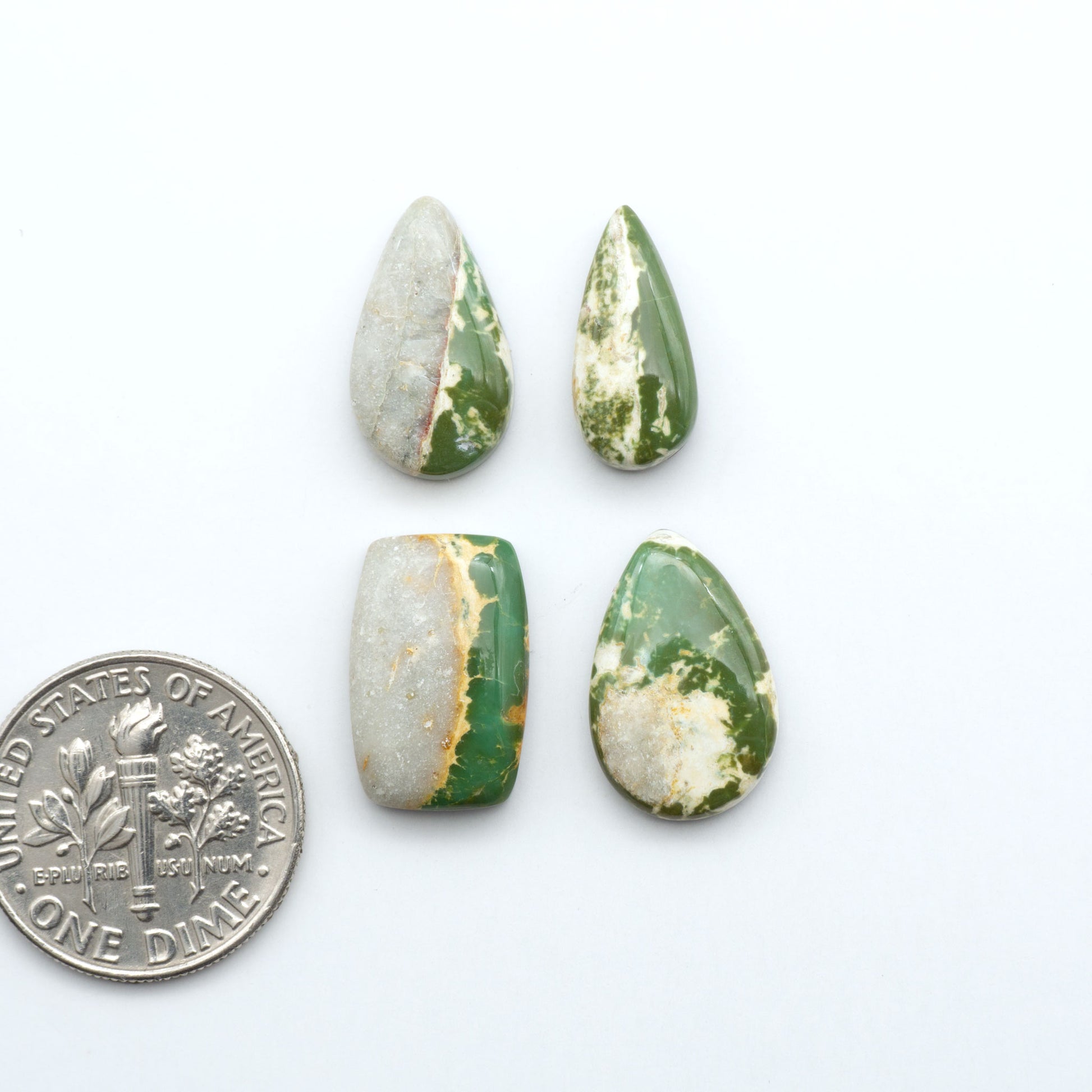 Royston Turquoise cabochons, blue-green color with natural matrix, polished stones on a white background, with a US dime for scale