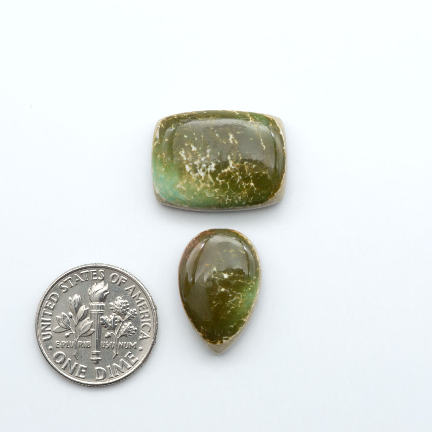 Royston Turquoise cabochons, blue-green color with natural matrix, polished stones on a white background, with a US dime for scale