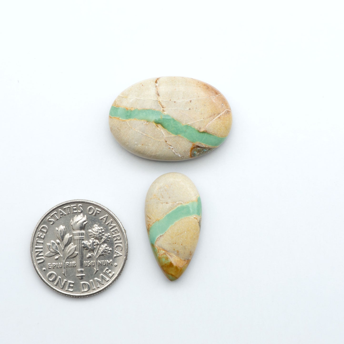 Royston Turquoise cabochons, blue-green color with natural matrix, polished stones on a white background, with a US dime for scale