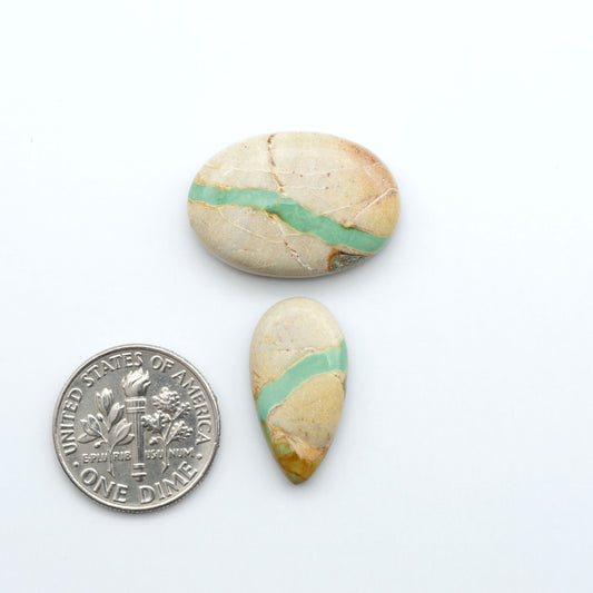 Royston Turquoise cabochons, blue-green color with natural matrix, polished stones on a white background, with a US dime for scale
