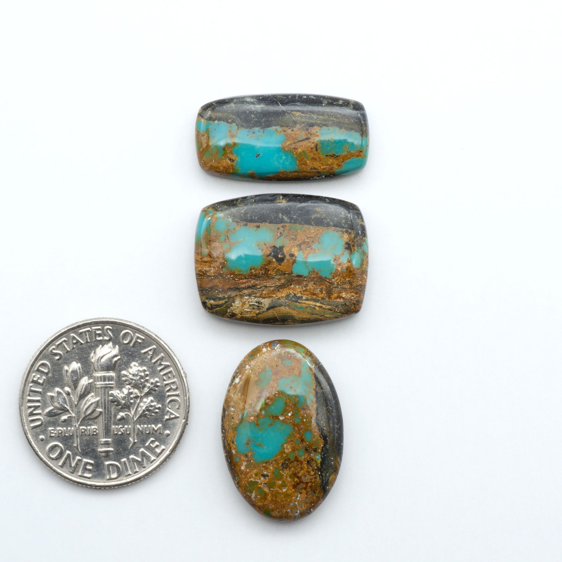 Black Jack turquoise cabochons, blue-green color with black matrix, polished stones on a white background with a US dime for scale