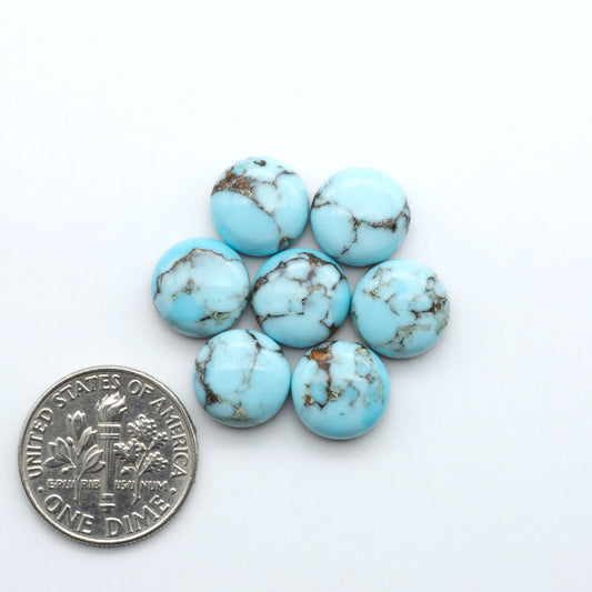 Pressed Turquoise nugget cabochons, composite material with a blue color and dark matrix on a white background, with a US dime for scale.
