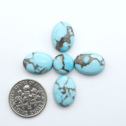 Pressed Turquoise nugget cabochons, composite material with a blue color and dark matrix on a white background, with a US dime for scale.